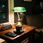 Cozy wooden desk with a steaming cup of tea, books, a lamp, a phone showing 10:43, and a comfortable armchair with a plaid blanket